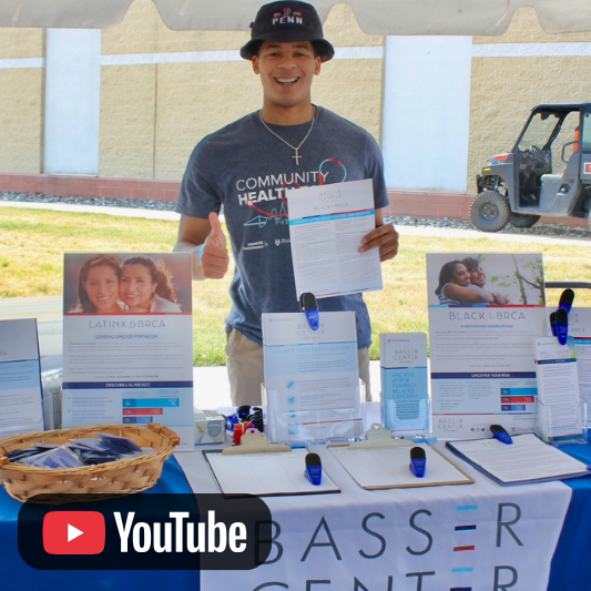 Video thumbnail featuring a person standing at a Basser Center information table and holding a document, with informational displays and a YouTube icon visible.