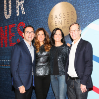 Group posing for picture on red carpet with Basser Center sign in background