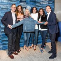 Group posing for a picture and displaying a jean jacket